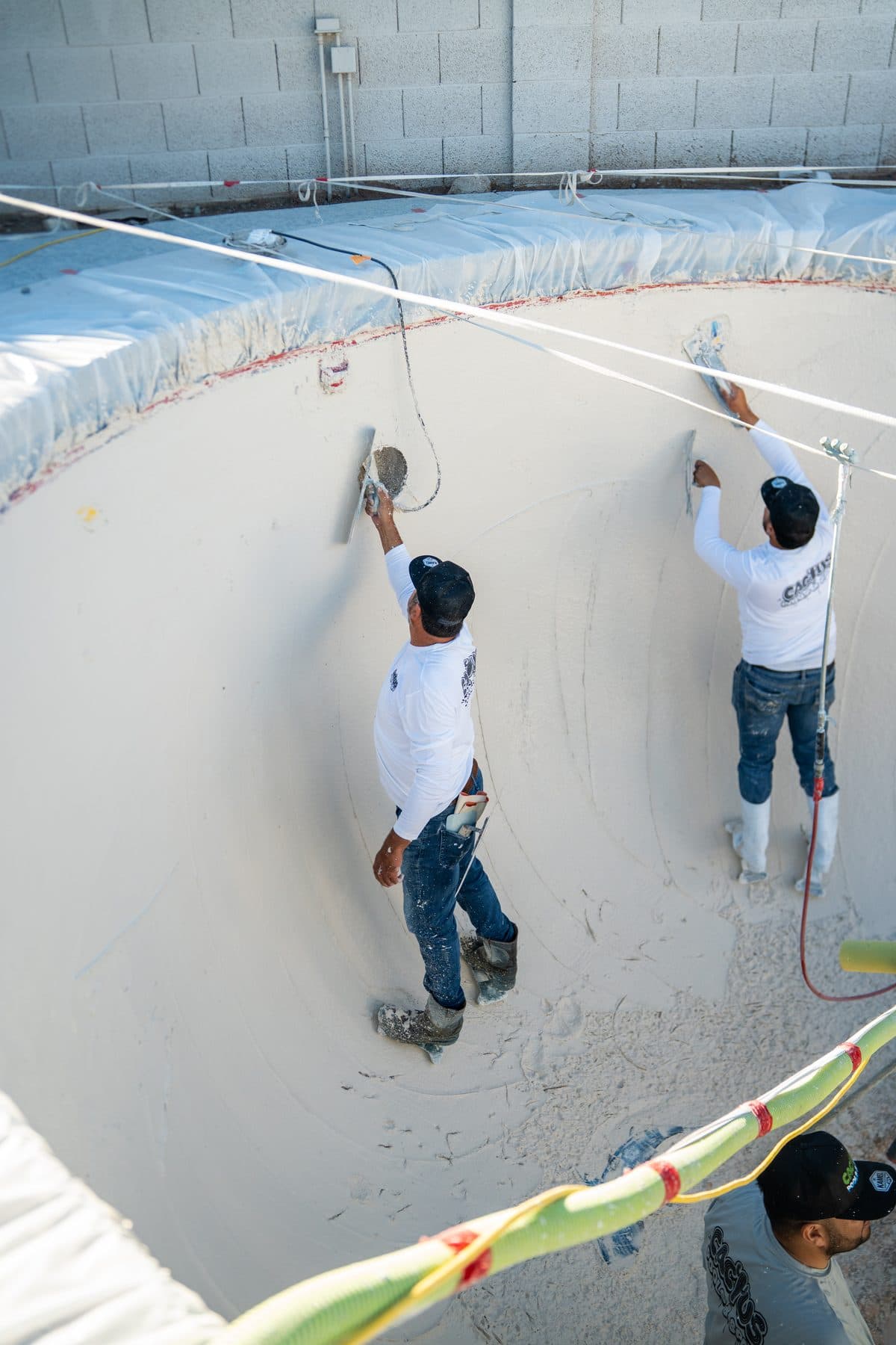 Two Cactus crew members smoothing a new finish on the pool walls
