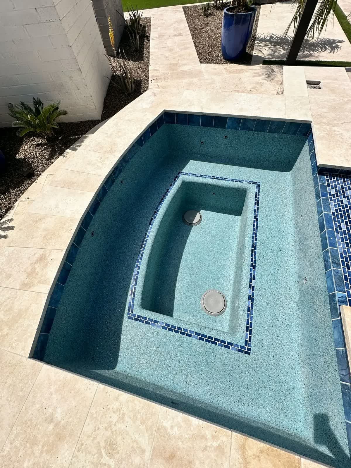 Empty pool with a fresh finish, blue tile trim and a travertine deck